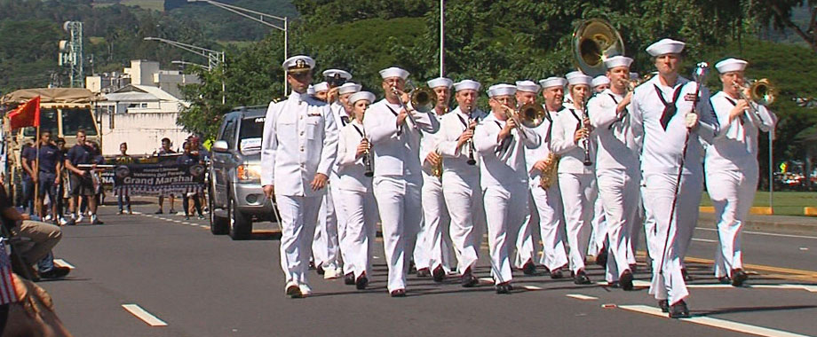 U.S. Pacific Fleet Band musicians march on a street during a parade.